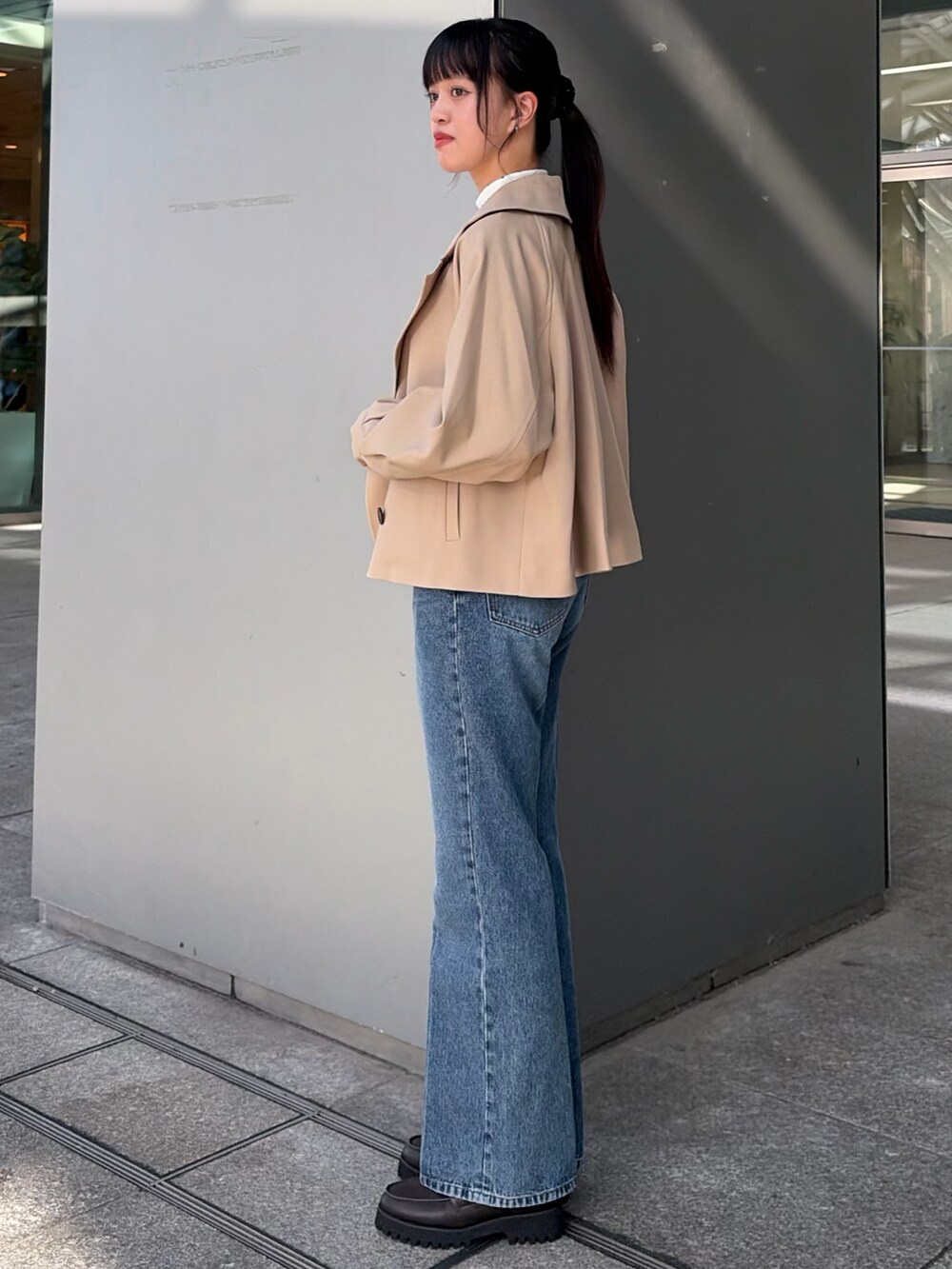ベージュ系のトレンチコート、ブルー系のその他パンツ、ホワイト系のTシャツ/カットソーを着用したレディースの秋コーディネートの4枚目の写真