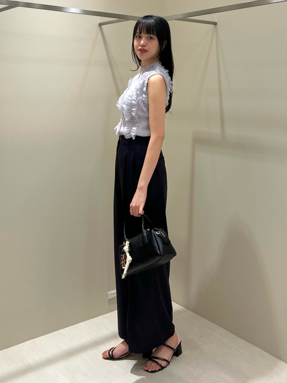 グレー系のニット/セーター、ブルー系のその他パンツ、ブラック系のボストンバッグを着用したレディースの夏コーディネートの3枚目の写真