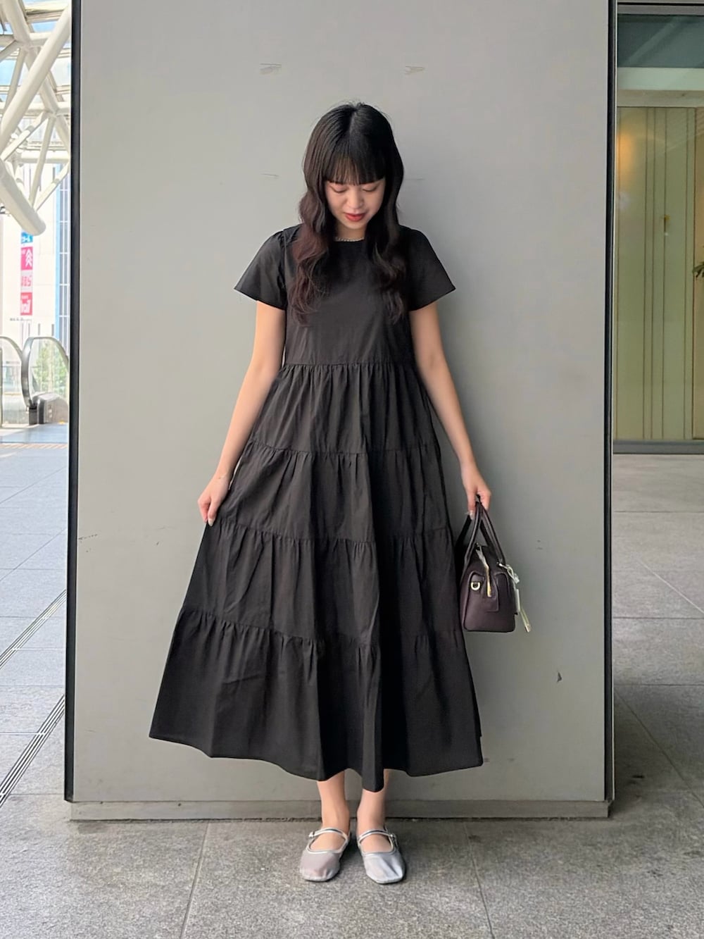 ブラック系のワンピース、ブラウン系のボストンバッグを着用したレディースの夏コーディネートの2枚目の写真