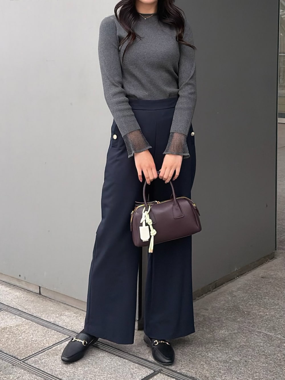 グレー系のニット/セーター、ブルー系のその他パンツ、ブラウン系のボストンバッグを着用したレディースの秋コーディネートの2枚目の写真
