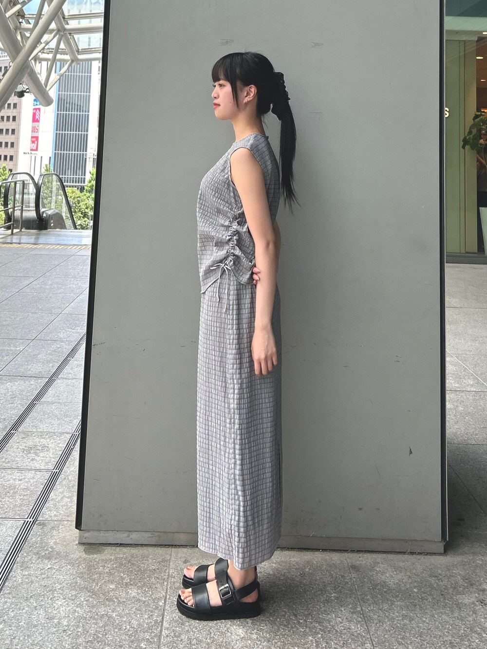 ブラック系のサンダル、グレー系のワンピースを着用したレディースの夏コーディネートの3枚目の写真