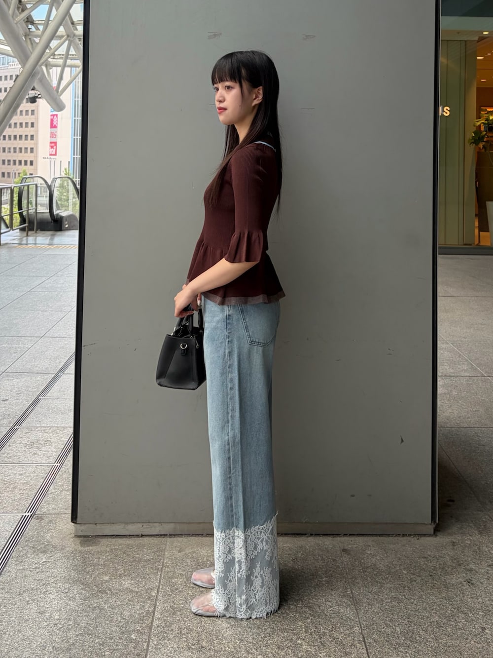 ブラウン系のニット/セーター、グリーン系のトートバッグ、ブルー系のデニムパンツを着用したレディースの夏コーディネートの3枚目の写真