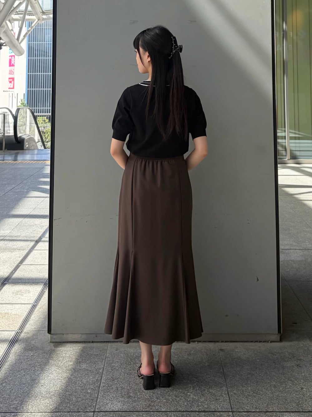 ブラック系のニット/セーター、ブラウン系のスカート、ベージュ系のトートバッグを着用したレディースの夏コーディネートの5枚目の写真