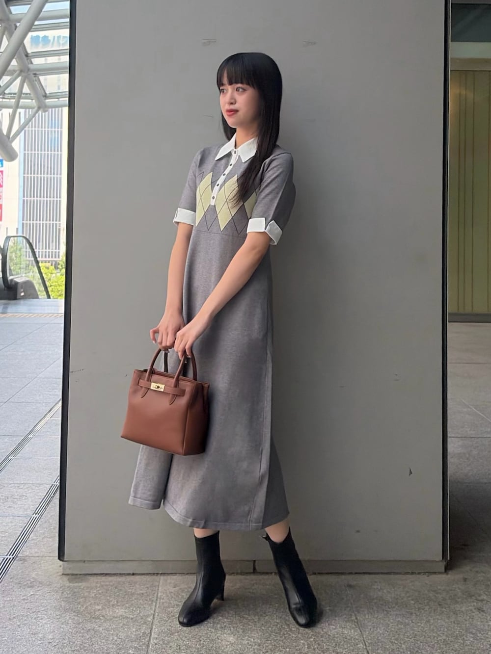 グレー系のワンピース、イエロー系のトートバッグ、ブラック系のブーツを着用したレディースの夏コーディネートの2枚目の写真