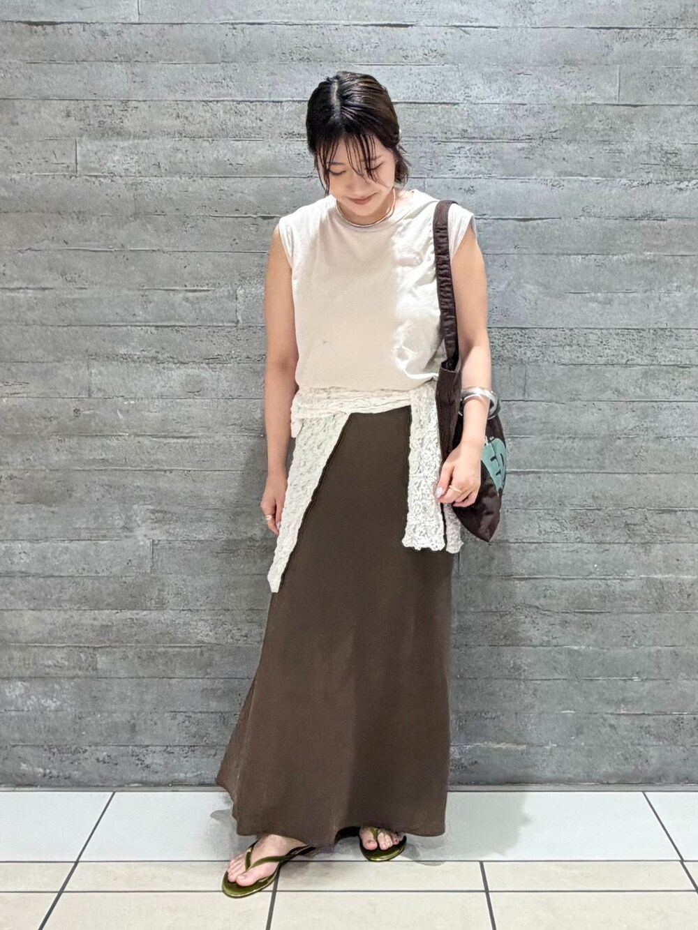 ブラウン系のトートバッグ、グリーン系のサンダルを着用したレディースの夏コーディネートの2枚目の写真