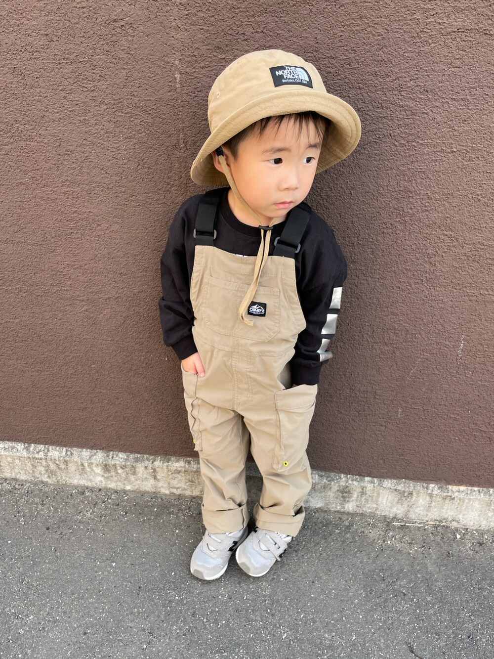 ベージュ系のオールインワン・サロペット、グレー系のスニーカー、ブラック系のTシャツ/カットソーを着用したキッズの春コーディネートの2枚目の写真