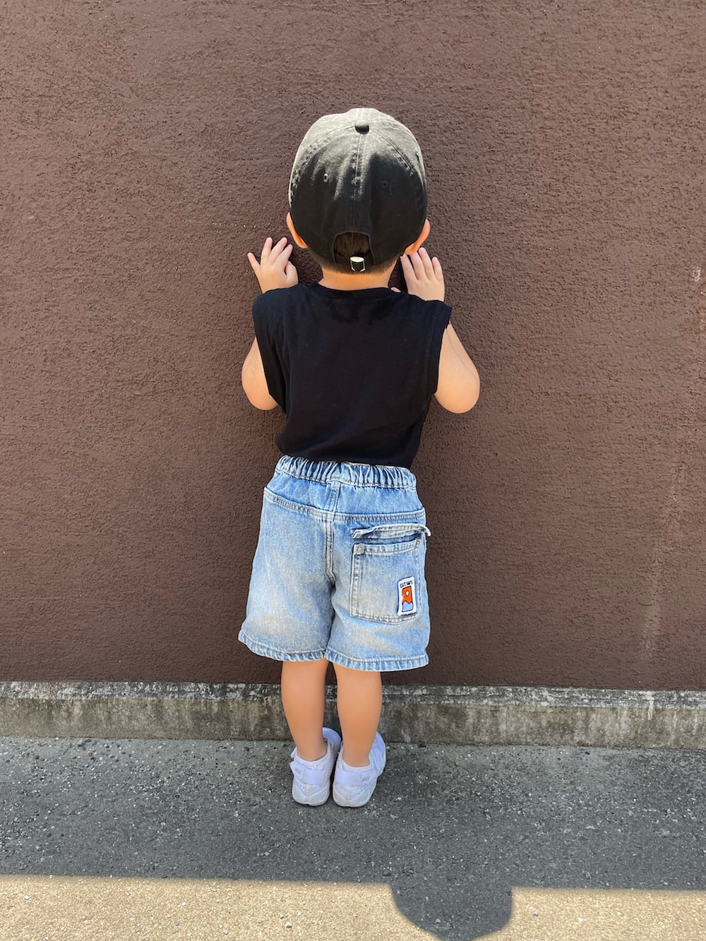 ブラック系のタンクトップ、ブルー系のデニムパンツ、ホワイト系のサンダルを着用したキッズの夏コーディネートの3枚目の写真