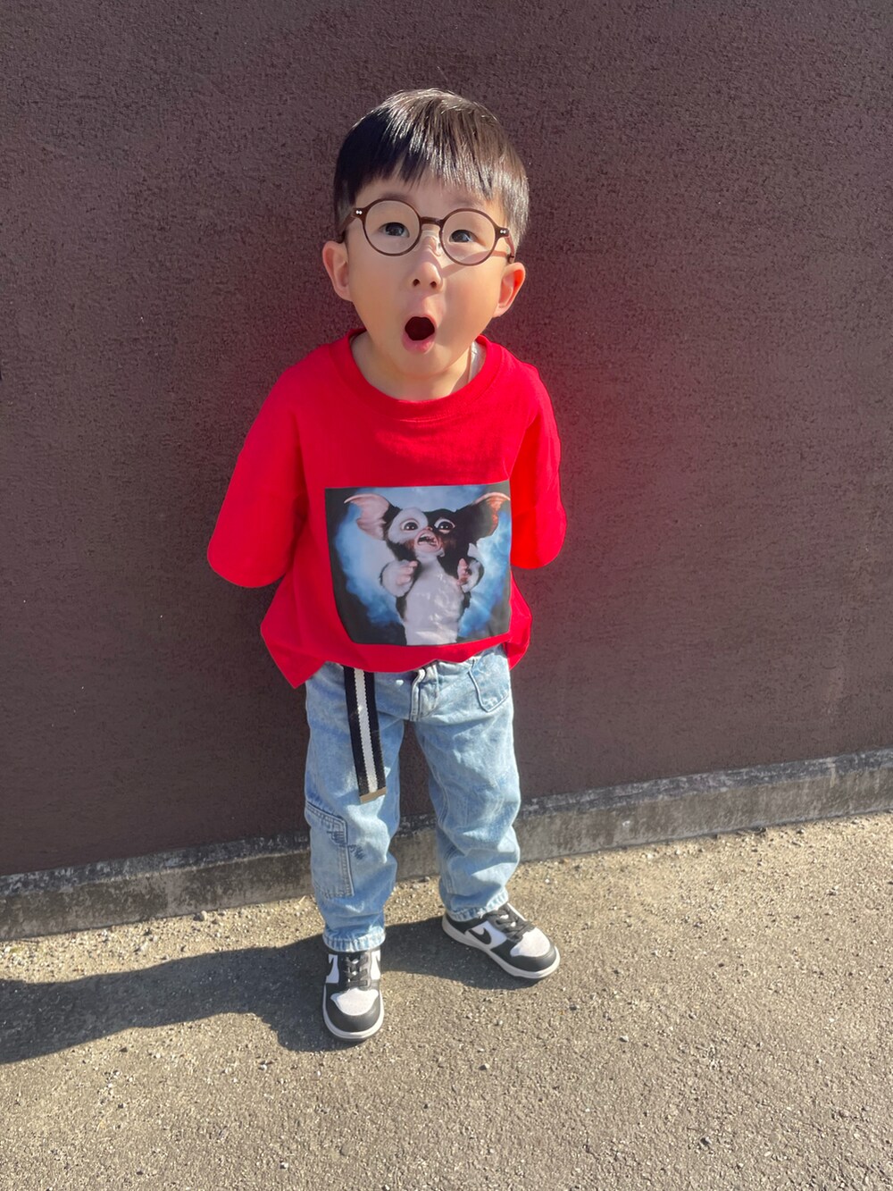 レッド系のTシャツ/カットソー、ブルー系のデニムパンツ、ブラック系のスニーカーを着用したキッズの春コーディネートの2枚目の写真