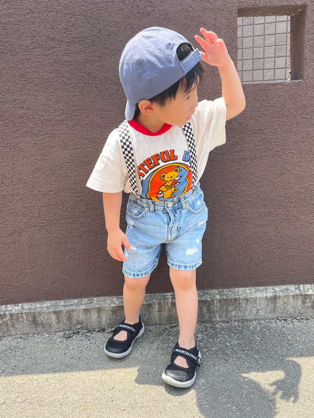 ブルー系のデニムパンツ、ブラック系のサンダル、レッド系のTシャツ/カットソーを着用したキッズの夏コーディネートの3枚目の写真