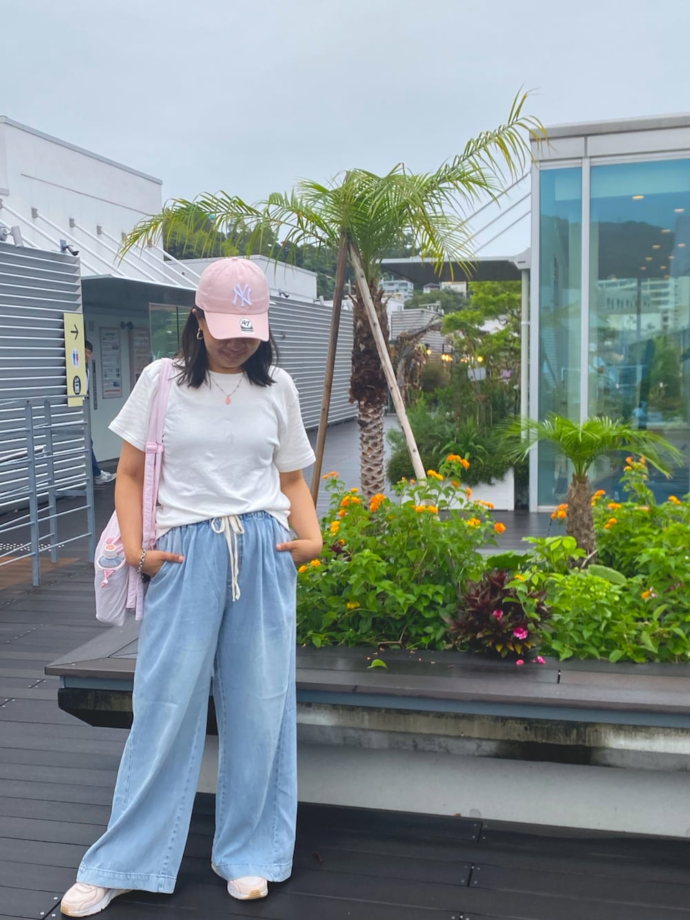 ブルー系のデニムパンツ、ホワイト系のTシャツ/カットソー、ピンク系のスニーカーを着用したレディースの秋コーディネートの3枚目の写真