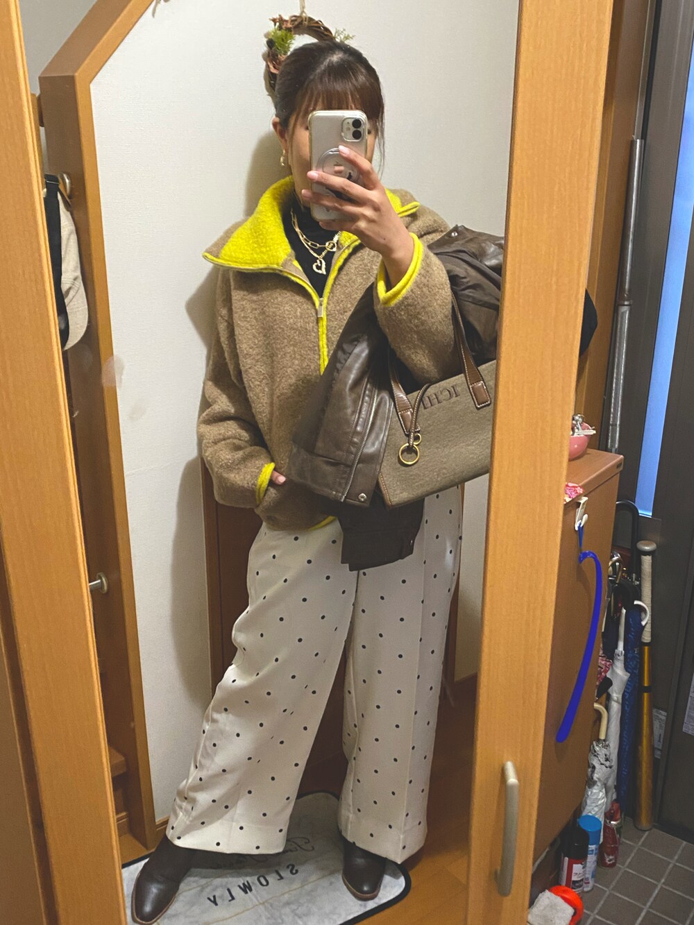 ベージュ系のニット/セーター、ブラウン系のバッグ、ホワイト系のスラックスを着用したレディースの冬コーディネートの2枚目の写真