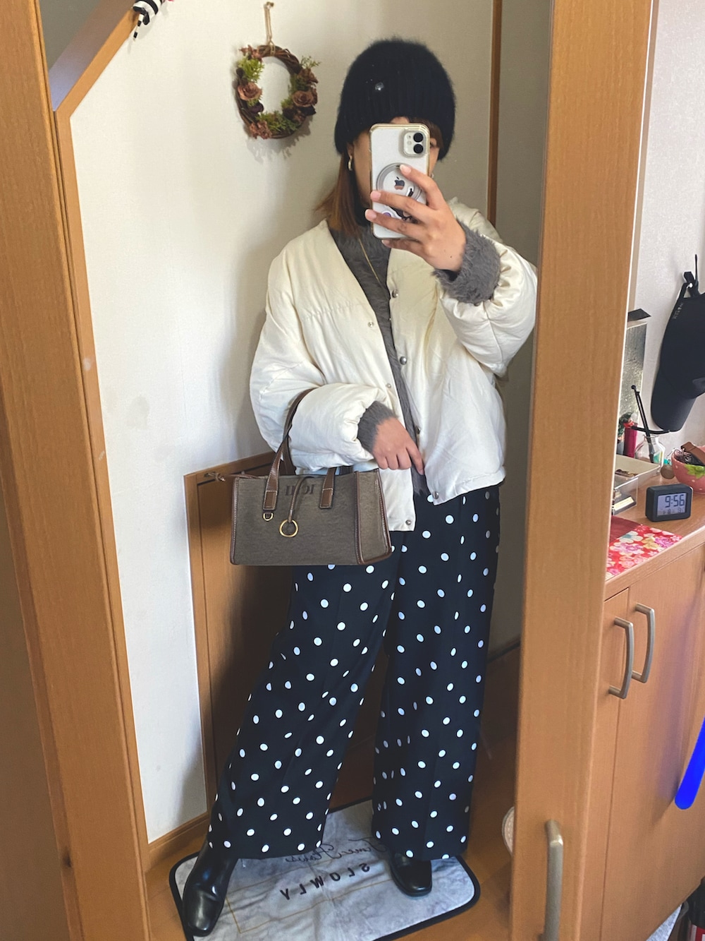 ブラック系のスラックス、ホワイト系のダウンジャケット/コート、ブラウン系のニット/セーターを着用したレディースの冬コーディネートの2枚目の写真