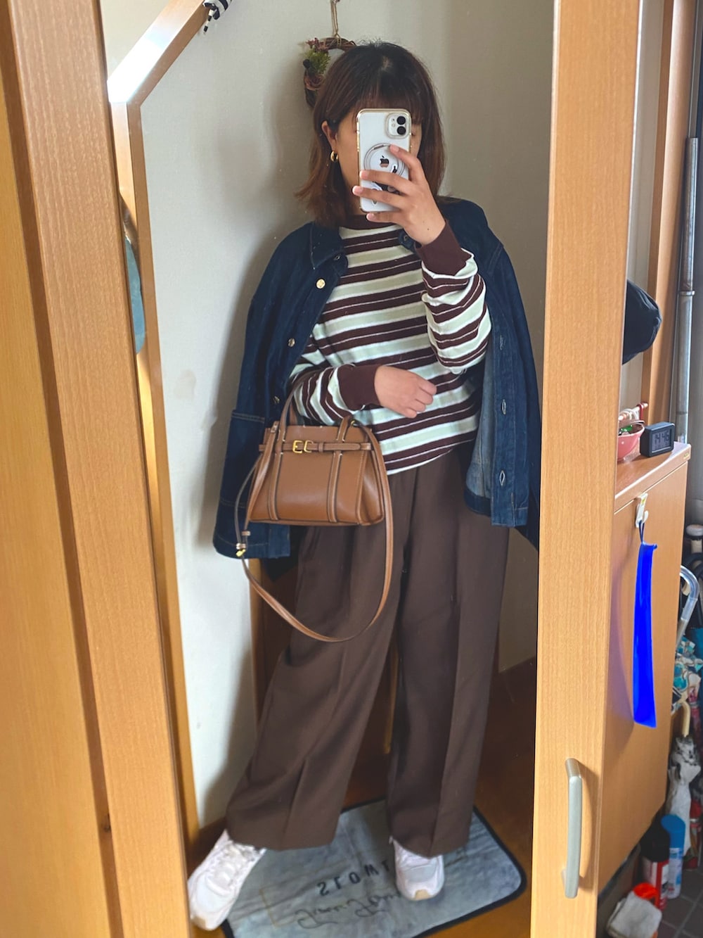 ブラウン系のスラックス、ピンク系のスニーカー、ブラウン系のニット/セーターを着用したレディースの春コーディネートの2枚目の写真