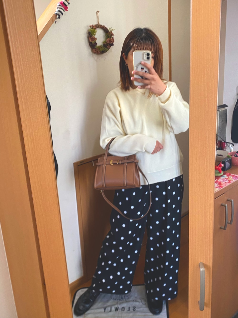 ブラック系のスラックス、ホワイト系のニット/セーター、ブラック系のローファーを着用したレディースの春コーディネートの2枚目の写真