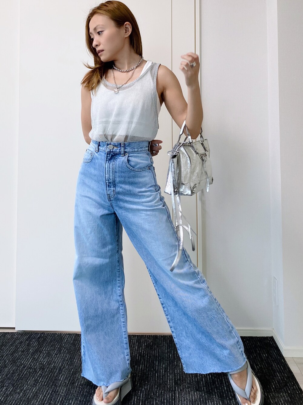 グレー系のサンダル、ブルー系のデニムパンツ、シルバー系のショルダーバッグを着用したレディースの夏コーディネートの3枚目の写真