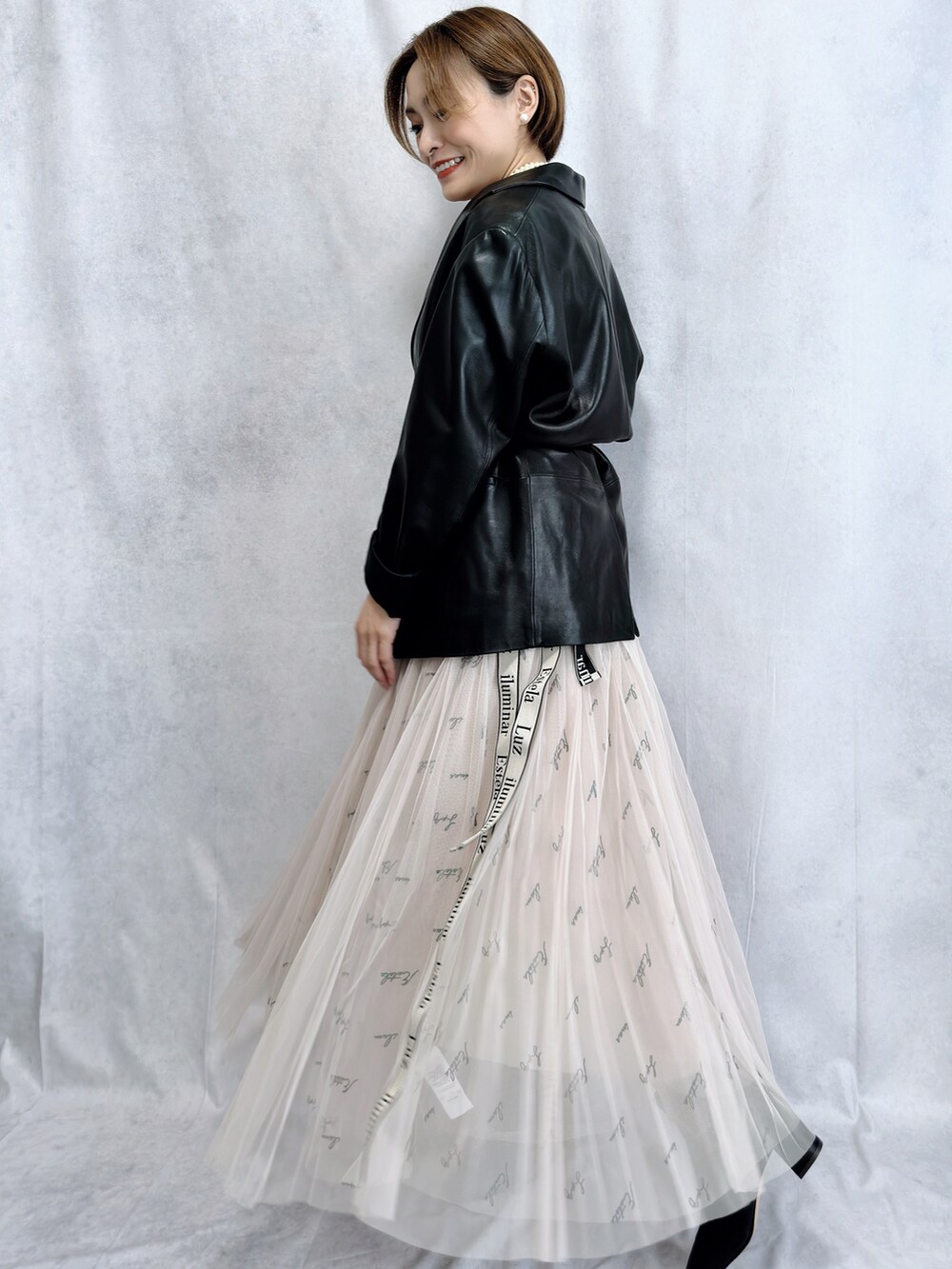 ブラック系のテーラードジャケット、ベージュ系のスカート、ブラック系のブーツを着用したレディースの冬コーディネートの5枚目の写真