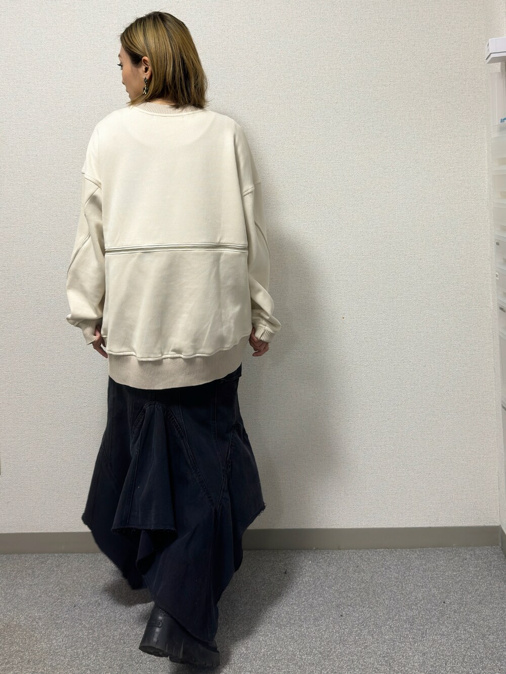 ホワイト系のニット/セーター、ブラック系のデニムスカート、ブラック系のブーツを着用したレディースの冬コーディネートの4枚目の写真