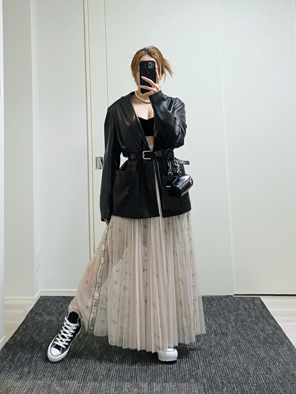 ブラック系のテーラードジャケット、ベージュ系のスカート、ブラック系のスニーカーを着用したレディースの冬コーディネートの2枚目の写真