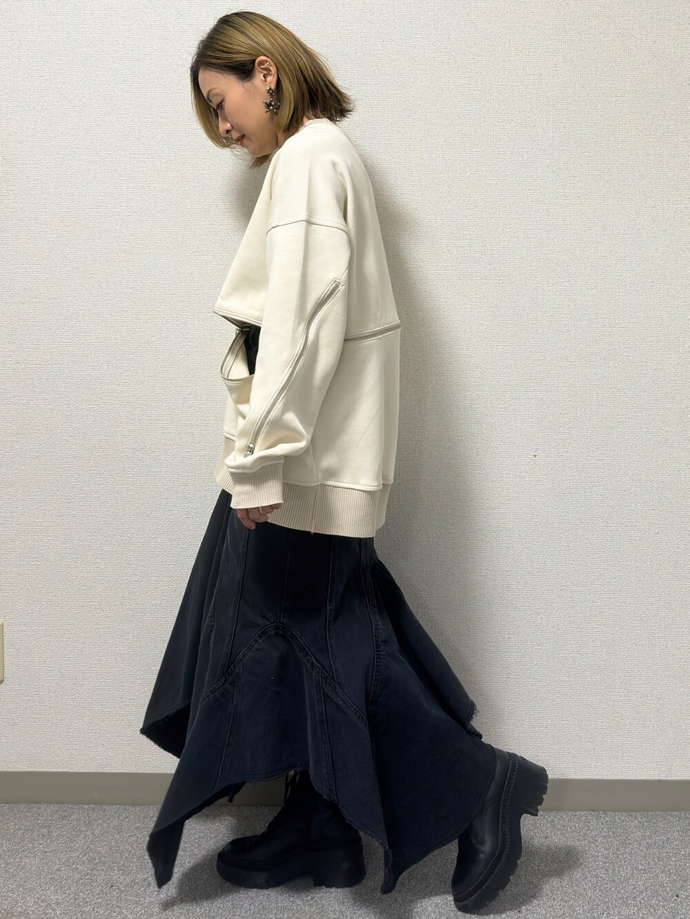 ホワイト系のニット/セーター、ブラック系のデニムスカート、ブラック系のブーツを着用したレディースの冬コーディネートの2枚目の写真