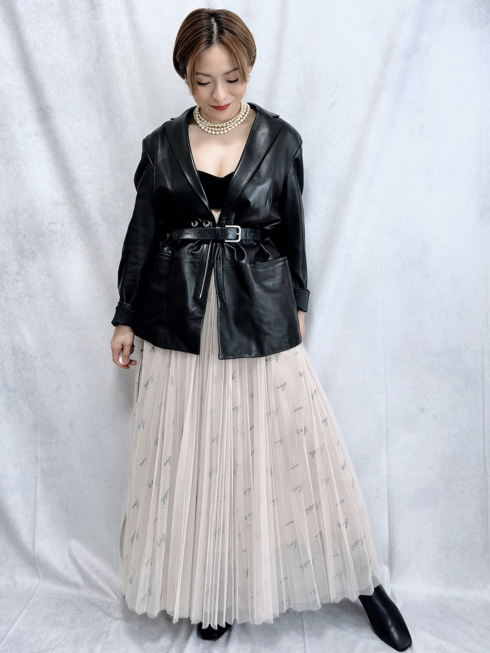 ブラック系のテーラードジャケット、ベージュ系のスカート、ブラック系のブーツを着用したレディースの冬コーディネートの2枚目の写真