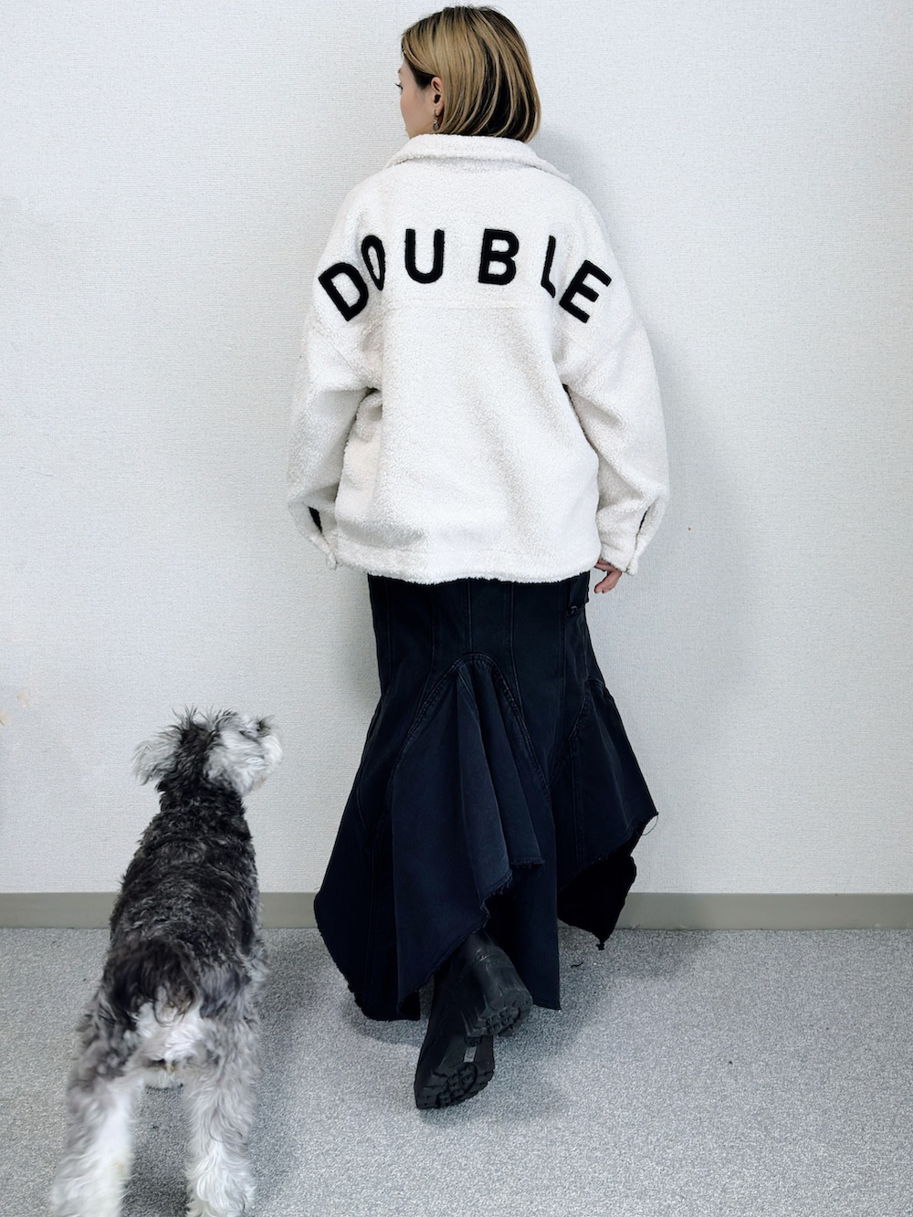 ホワイト系のその他アウター、ブラック系のデニムスカート、ブラック系のブーツを着用したレディースの冬コーディネートの2枚目の写真