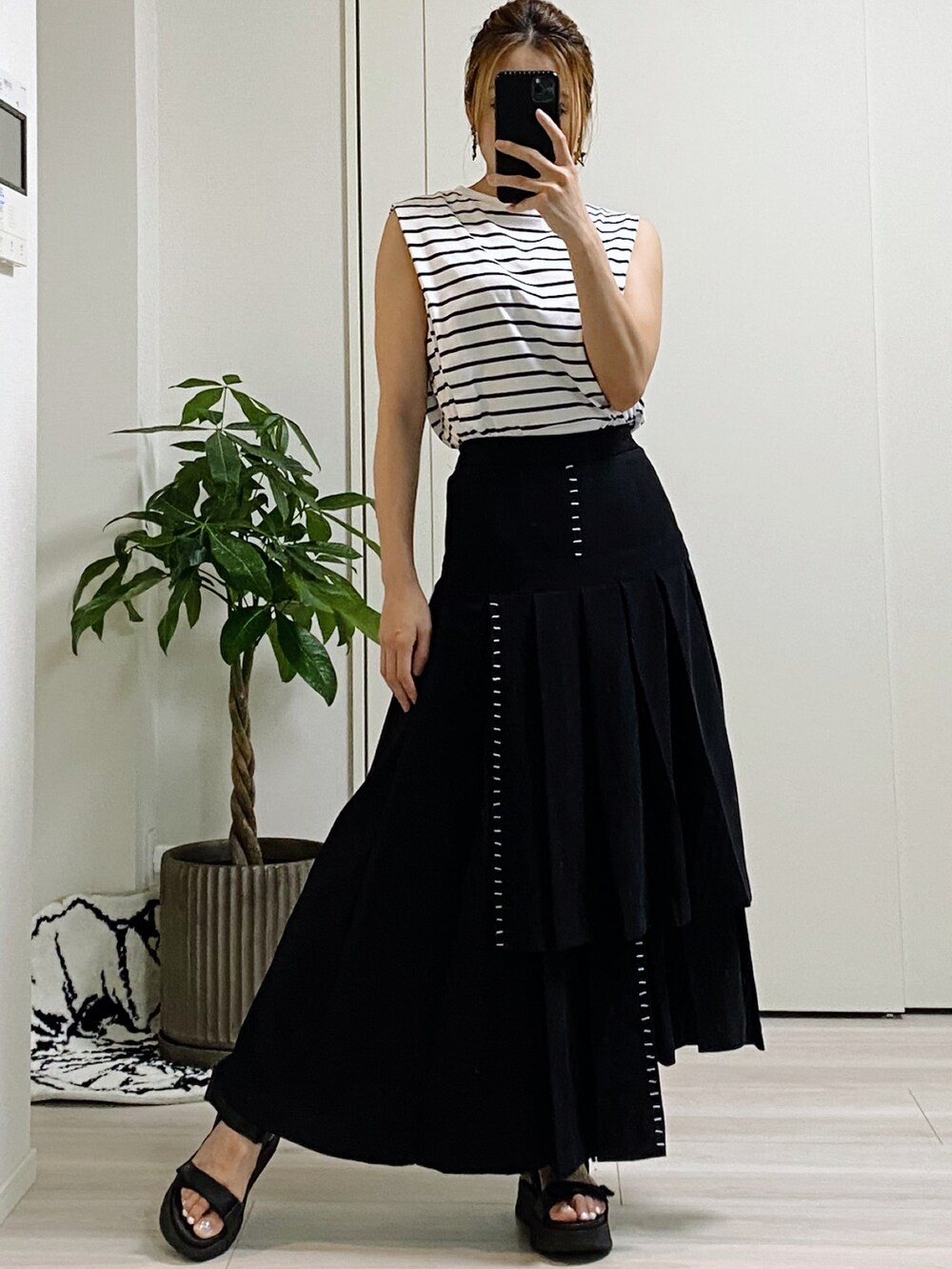 ブラック系のスカート、ホワイト系のトップス、ブラック系のサンダルを着用したレディースの夏コーディネートの2枚目の写真