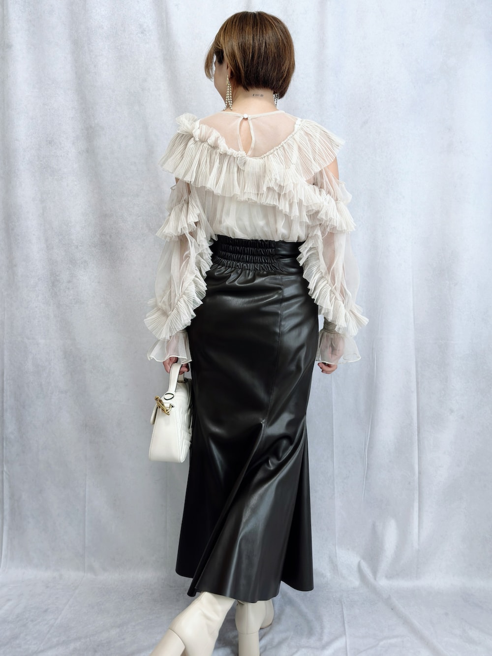 ホワイト系のトップス、ブラウン系のスカート、ホワイト系のブーツを着用したレディースの冬コーディネートの2枚目の写真