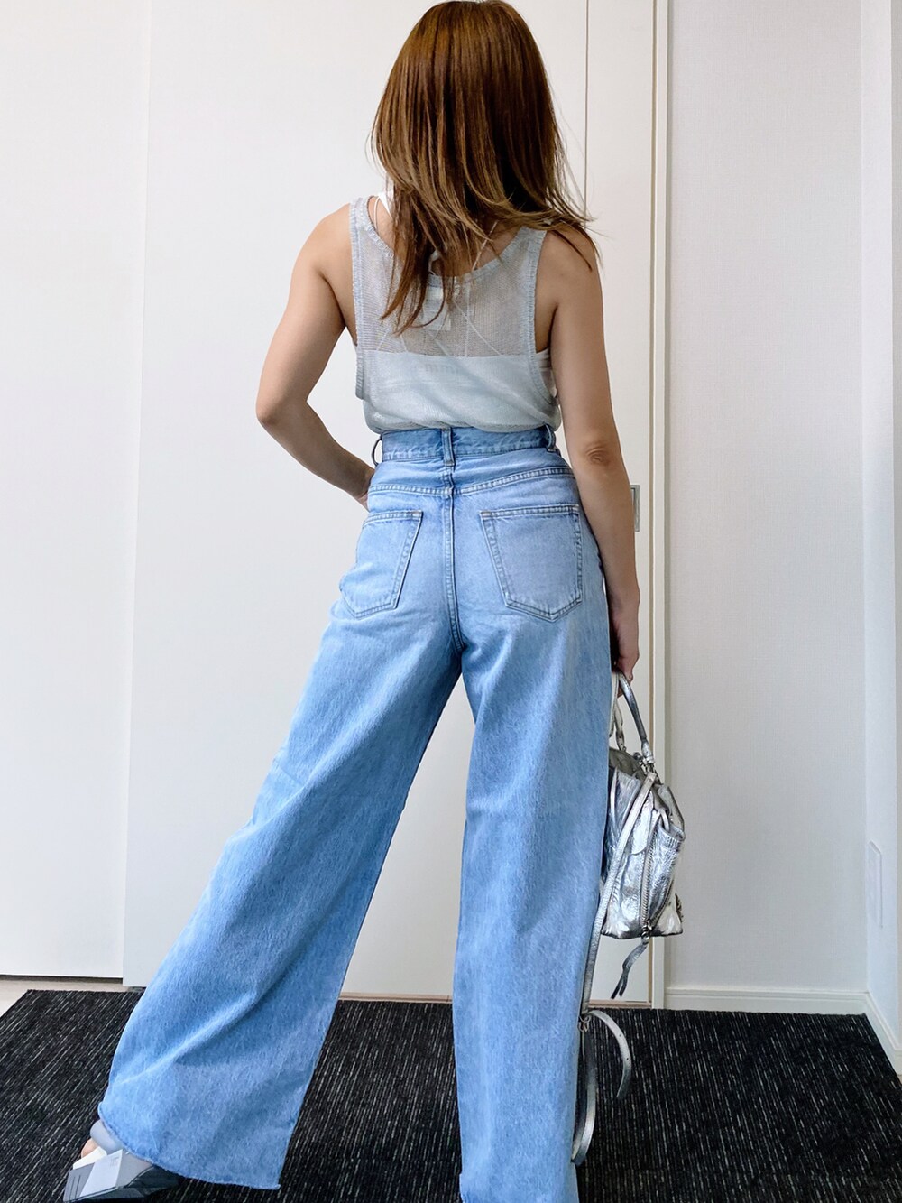 グレー系のサンダル、ブルー系のデニムパンツ、シルバー系のショルダーバッグを着用したレディースの夏コーディネートの5枚目の写真