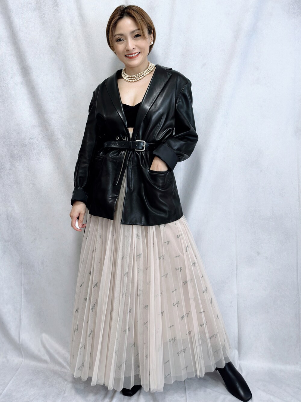 ブラック系のテーラードジャケット、ベージュ系のスカート、ブラック系のブーツを着用したレディースの冬コーディネートの3枚目の写真