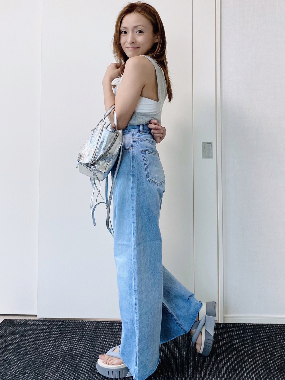 グレー系のサンダル、ブルー系のデニムパンツ、シルバー系のショルダーバッグを着用したレディースの夏コーディネートの2枚目の写真