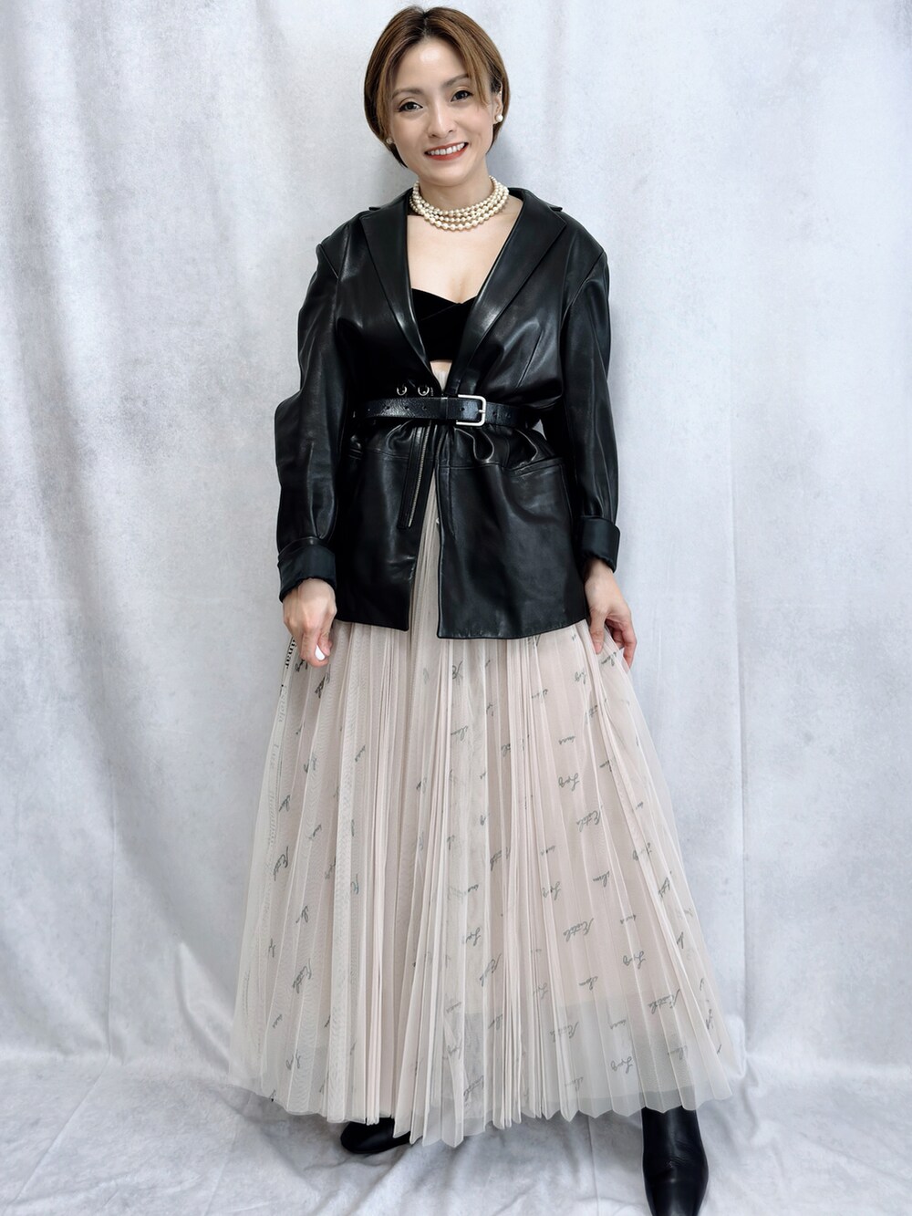 ブラック系のテーラードジャケット、ベージュ系のスカート、ブラック系のブーツを着用したレディースの冬コーディネートの4枚目の写真