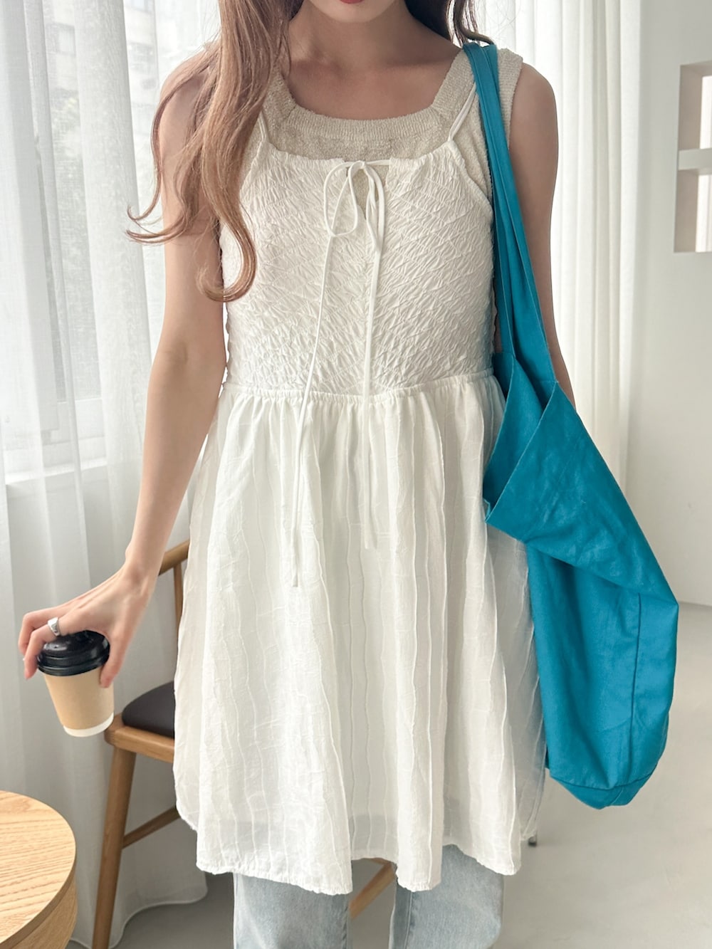 ホワイト系のチュニック、ホワイト系のタンクトップ、ブルー系のデニムパンツを着用したレディースの夏コーディネートの2枚目の写真