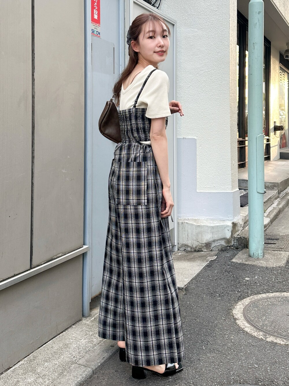 ブラウン系のショルダーバッグ、ブラック系のサロペット/オーバーオール、ホワイト系のTシャツ/カットソーを着用したレディースの春コーディネートの2枚目の写真