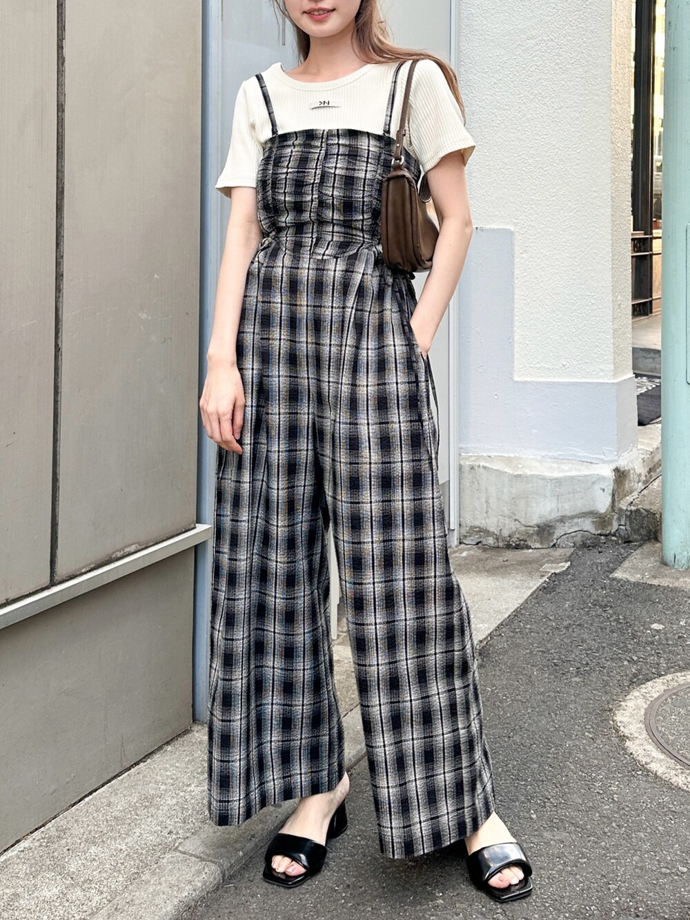 ブラウン系のショルダーバッグ、ブラック系のサロペット/オーバーオール、ホワイト系のTシャツ/カットソーを着用したレディースの春コーディネートの3枚目の写真