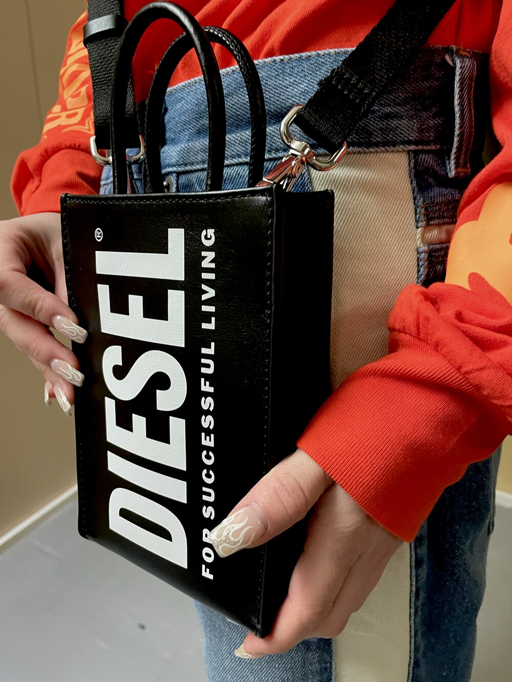 オレンジ系のTシャツ/カットソー、ブルー系のデニムパンツ、ブラック系のショルダーバッグを着用したレディースの春コーディネートの2枚目の写真