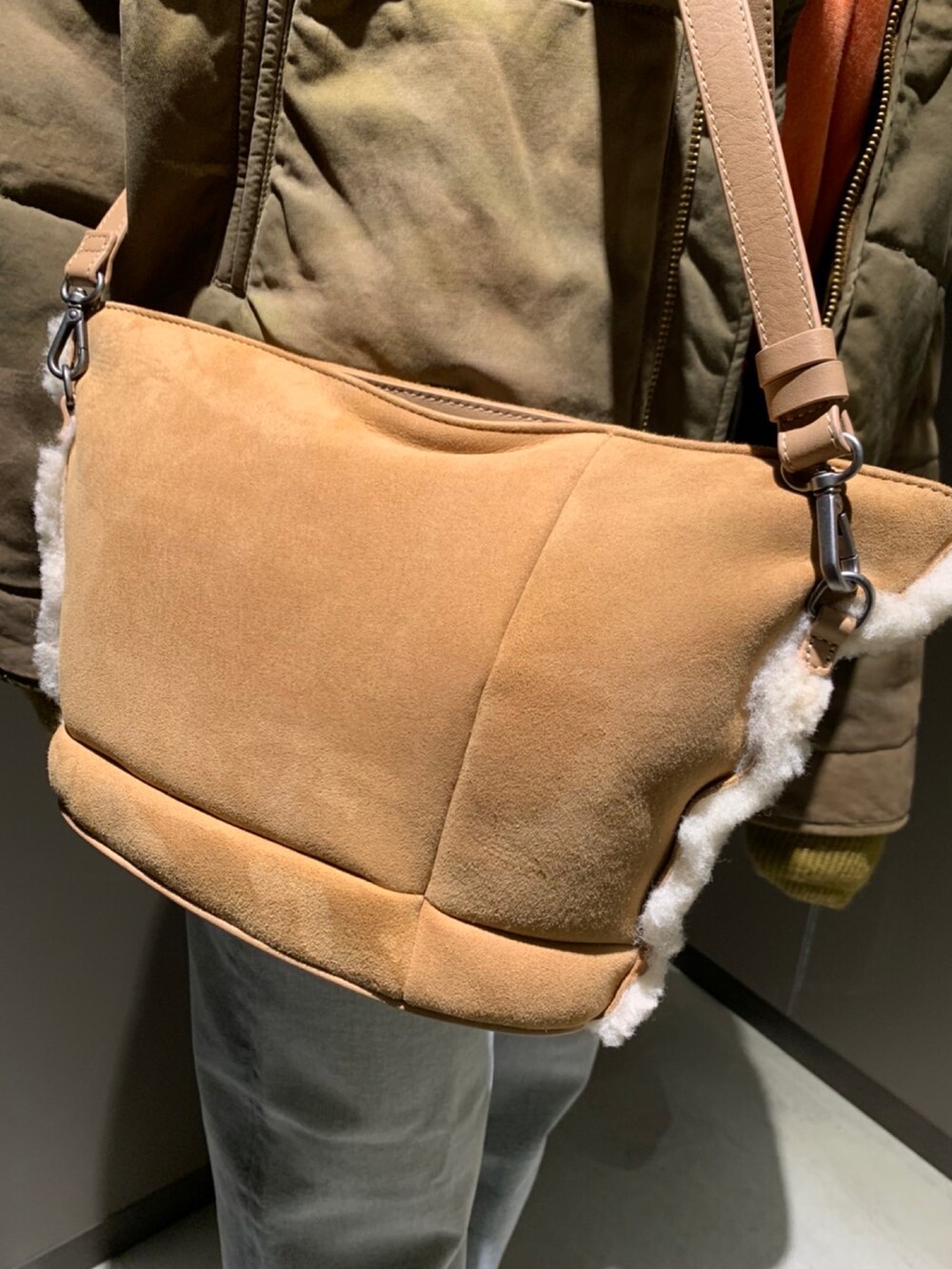 ブルー系のデニムパンツ、オレンジ系のニット/セーター、ブラウン系のジャケット/アウターを着用したレディースの秋コーディネートの2枚目の写真