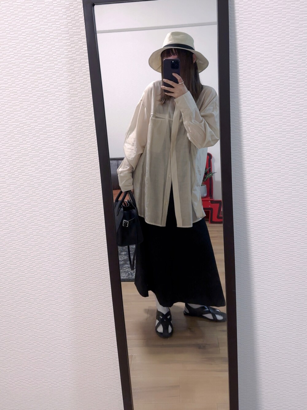 ブラック系のスカート、ブラック系のバッグ、ブラック系のサンダルを着用したレディースの春コーディネートの2枚目の写真