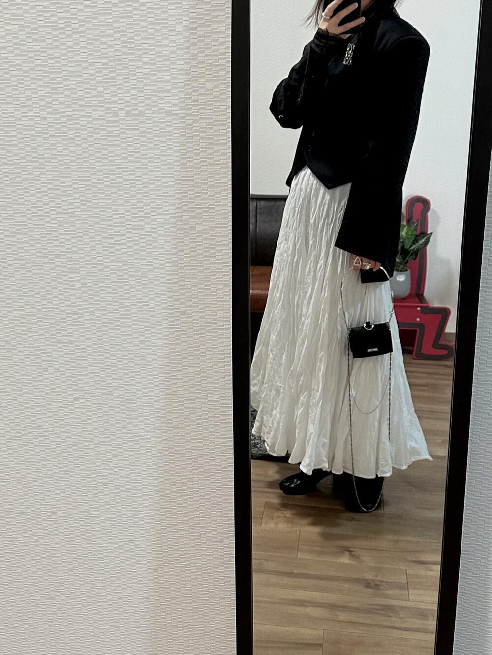 ブラック系のジャケット/アウター、ホワイト系のスカート、ブルー系のデニムパンツを着用したレディースの秋コーディネートの2枚目の写真