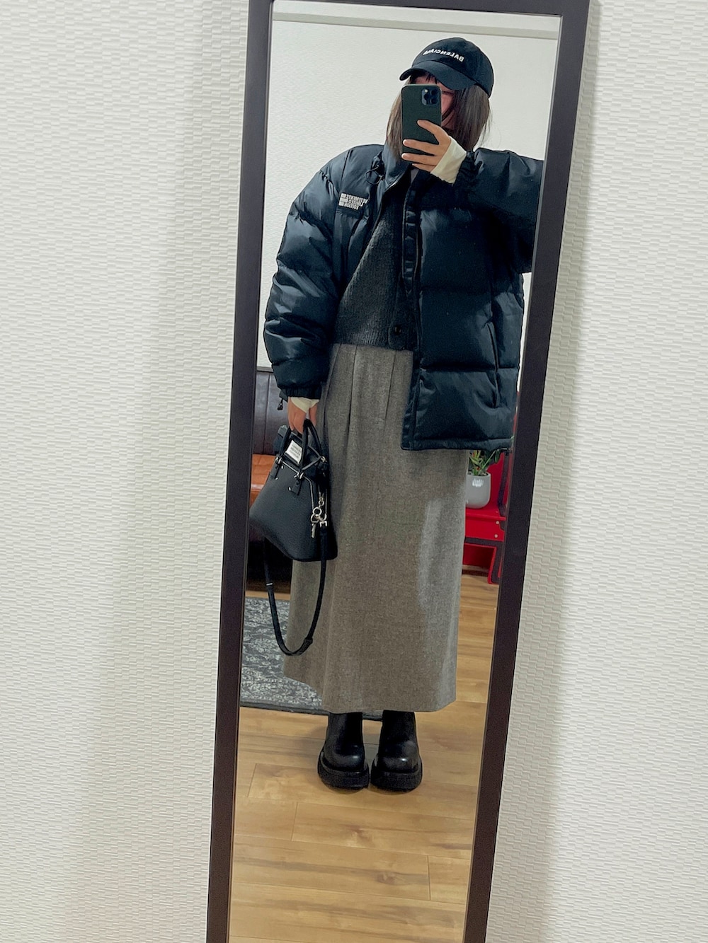 グレー系のベスト、グレー系のスカート、ブラック系のブーツを着用したレディースの冬コーディネートの2枚目の写真