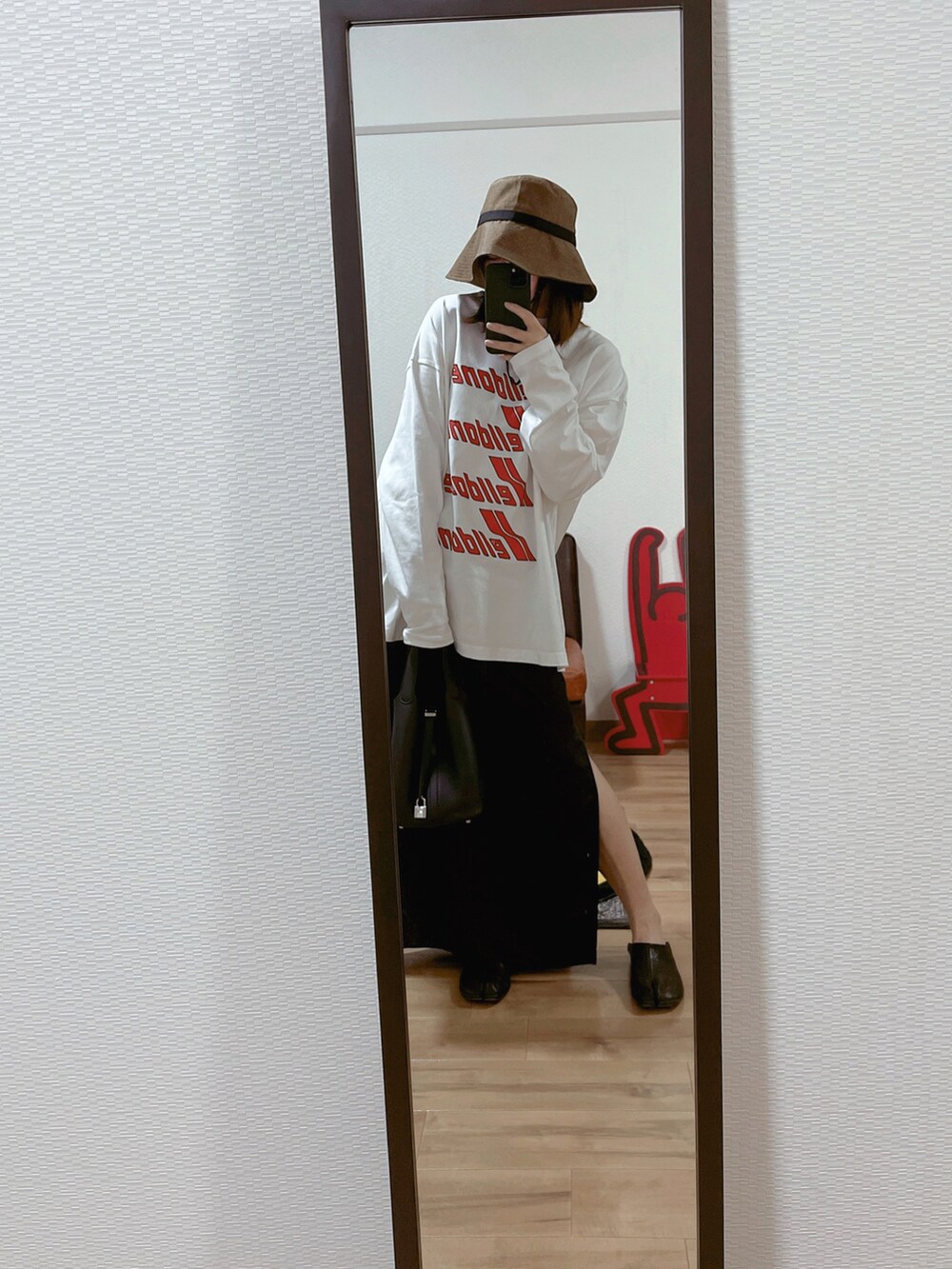 ホワイト系のTシャツ/カットソー、ブラック系のバッグ、ブラック系のスカートを着用したレディースの秋コーディネートの2枚目の写真