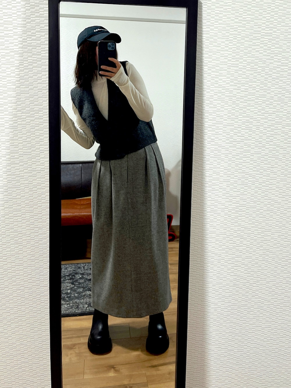 グレー系のベスト、グレー系のスカート、ブラック系のブーツを着用したレディースの冬コーディネートの3枚目の写真