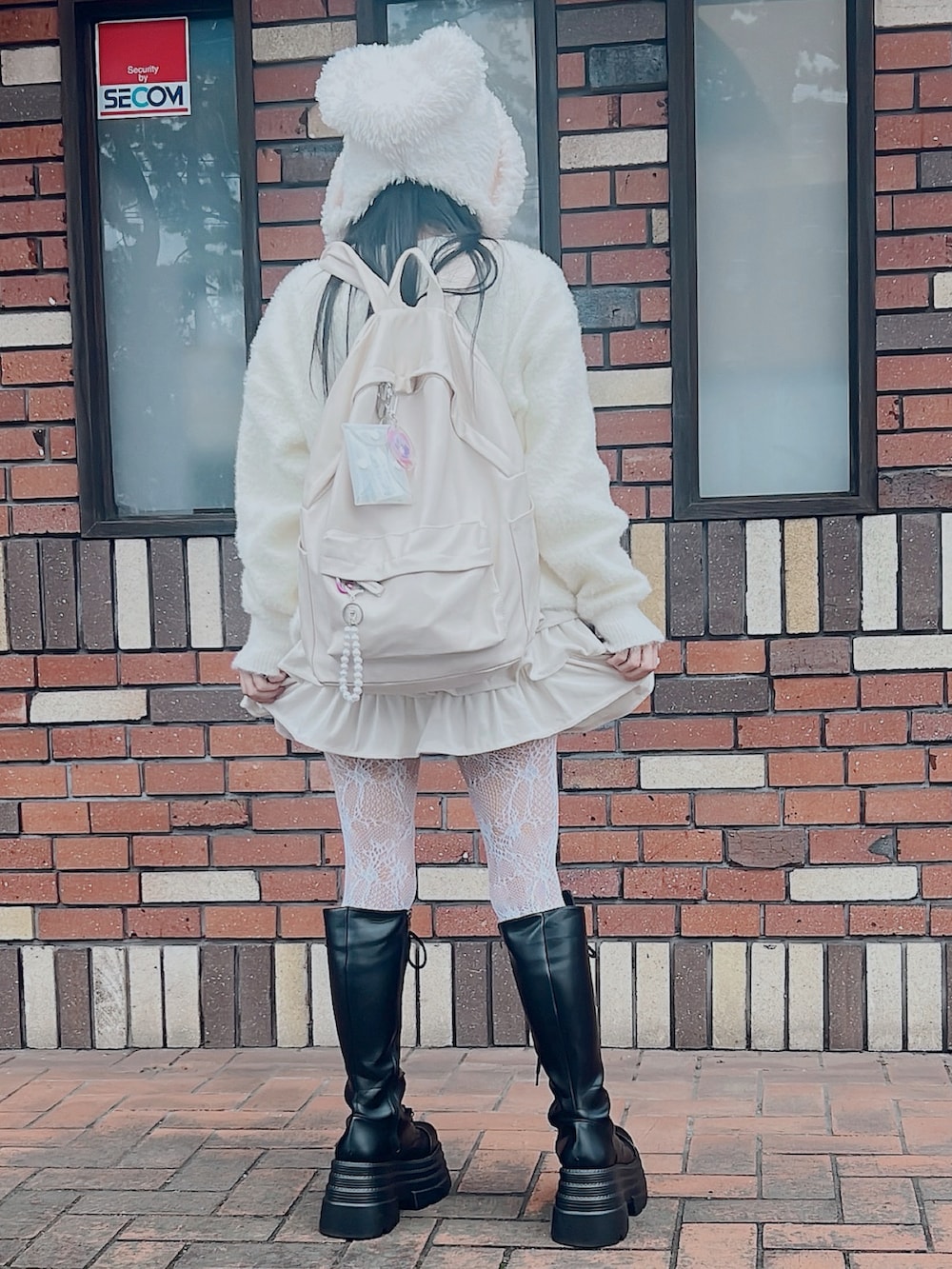 ホワイト系のニット/セーター、ホワイト系のスカート、ブラック系のブーツを着用したレディースの秋コーディネートの2枚目の写真