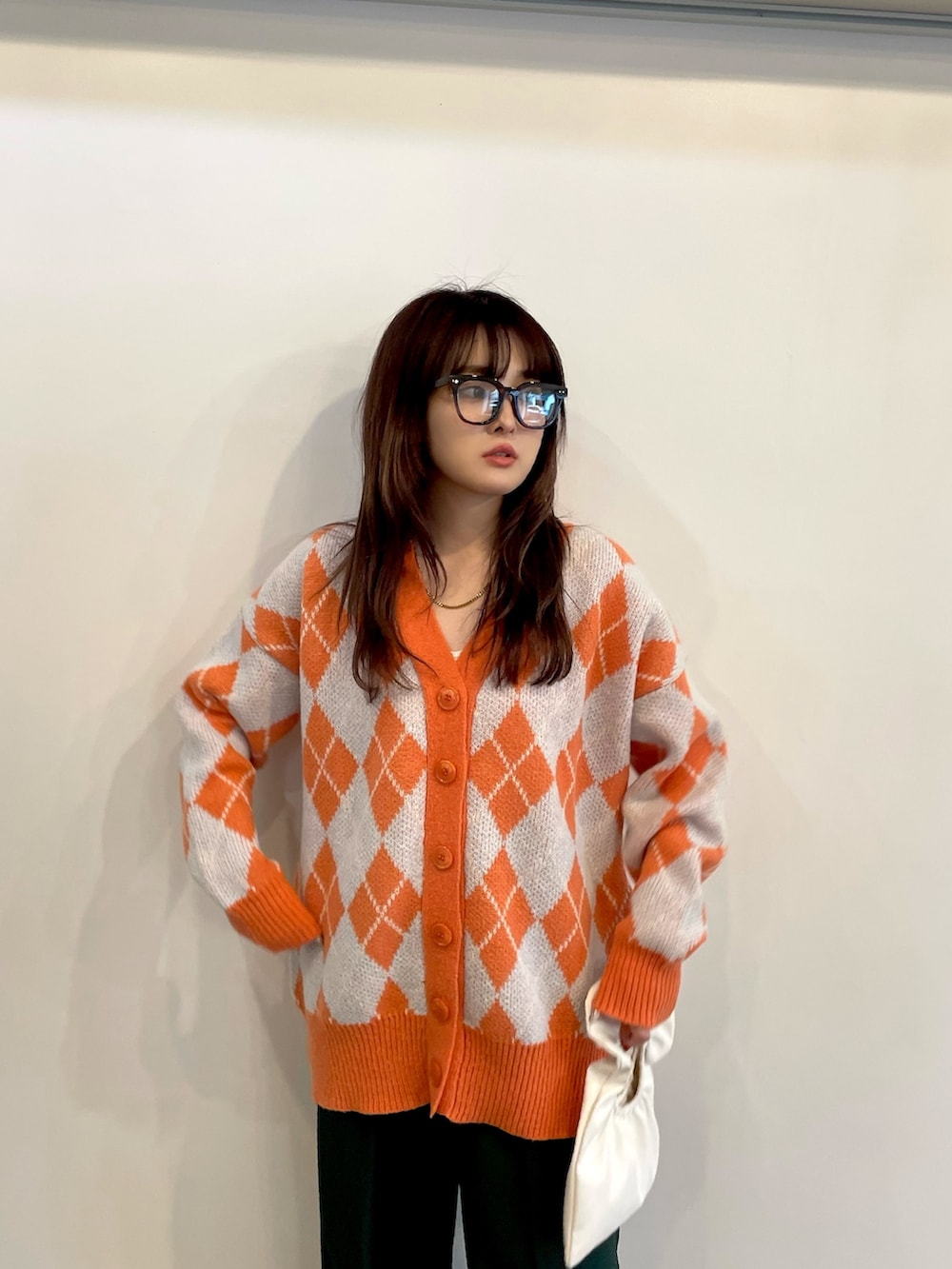 オレンジ系のカーディガン/ボレロ、グリーン系のスラックス、ホワイト系のスニーカーを着用したレディースの秋コーディネートの2枚目の写真