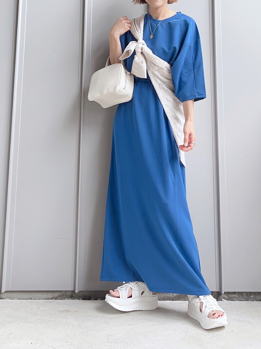 ブルー系のワンピース、ホワイト系のボストンバッグ、ホワイト系のサンダルを着用したレディースの夏コーディネートの3枚目の写真