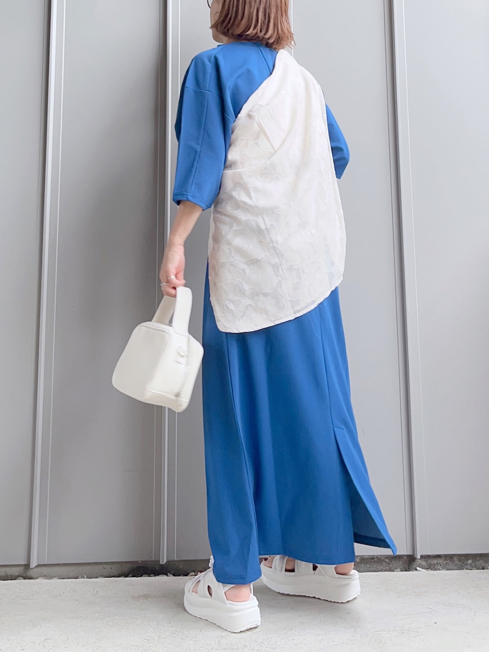 ブルー系のワンピース、ホワイト系のボストンバッグ、ホワイト系のサンダルを着用したレディースの夏コーディネートの4枚目の写真