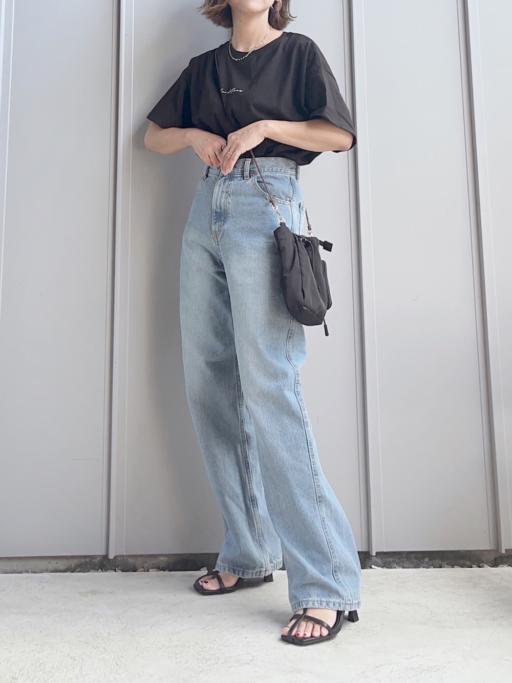 ブラック系のTシャツ/カットソー、ブルー系のデニムパンツ、ブラック系のショルダーバッグを着用したレディースの夏コーディネートの2枚目の写真