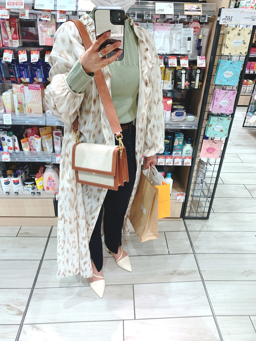 ベージュ系のワンピース、ブルー系のデニムパンツ、ホワイト系のパンプスを着用したレディースの春コーディネートの3枚目の写真