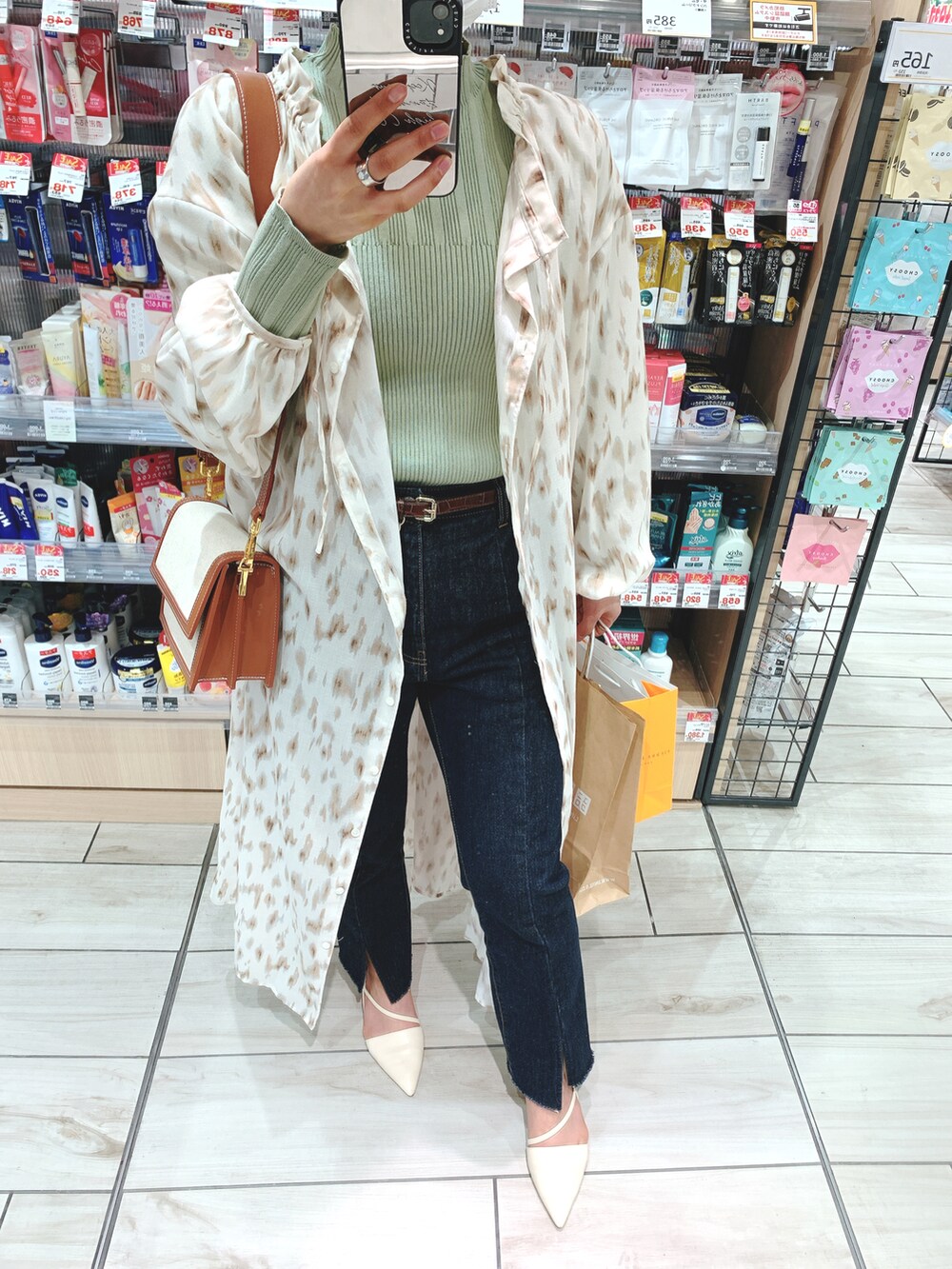 ベージュ系のワンピース、ブルー系のデニムパンツ、ホワイト系のパンプスを着用したレディースの春コーディネートの2枚目の写真