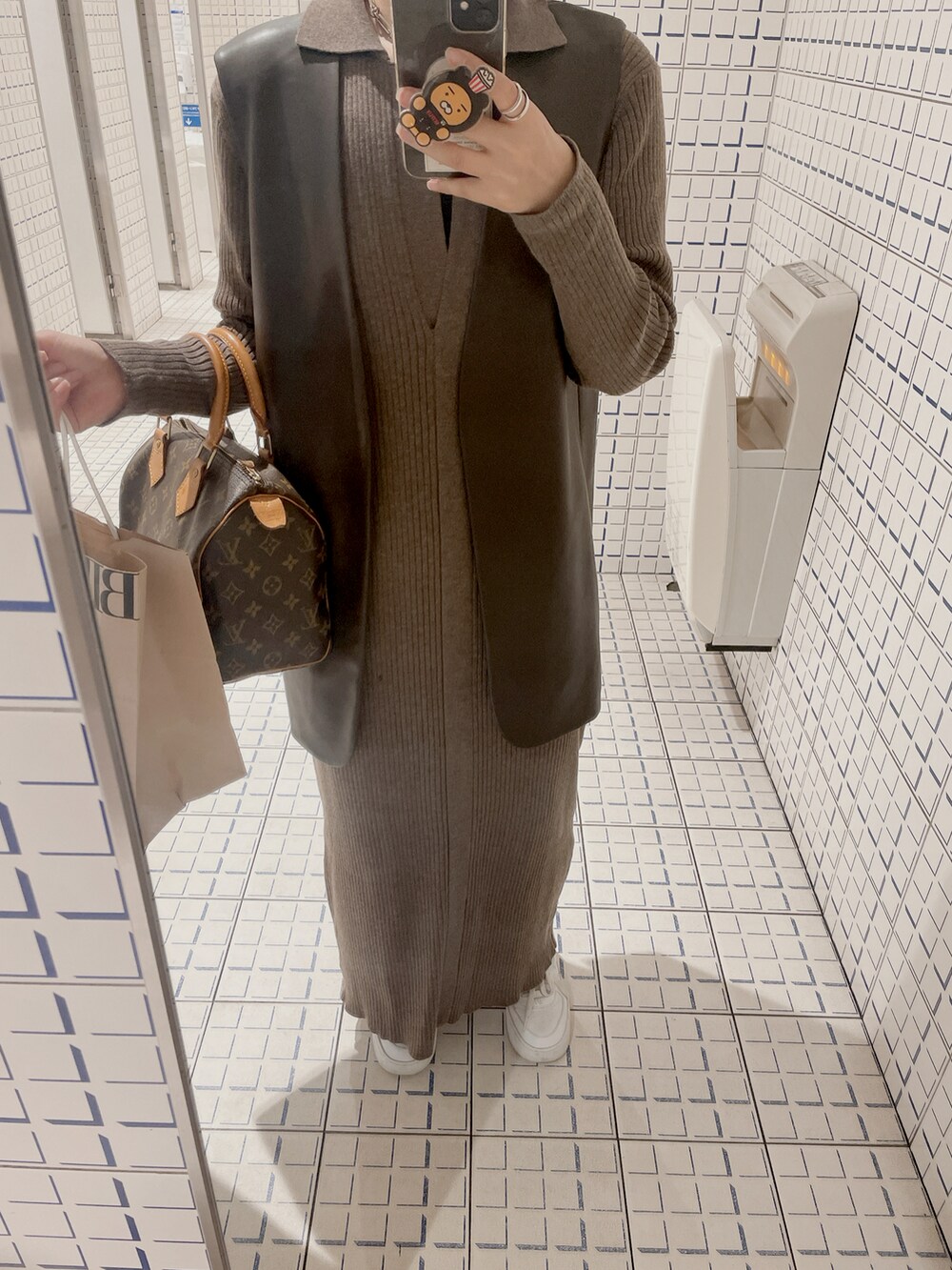 ブラウン系のワンピース、ホワイト系のスニーカー、ブラウン系のベストを着用したレディースの秋コーディネートの2枚目の写真