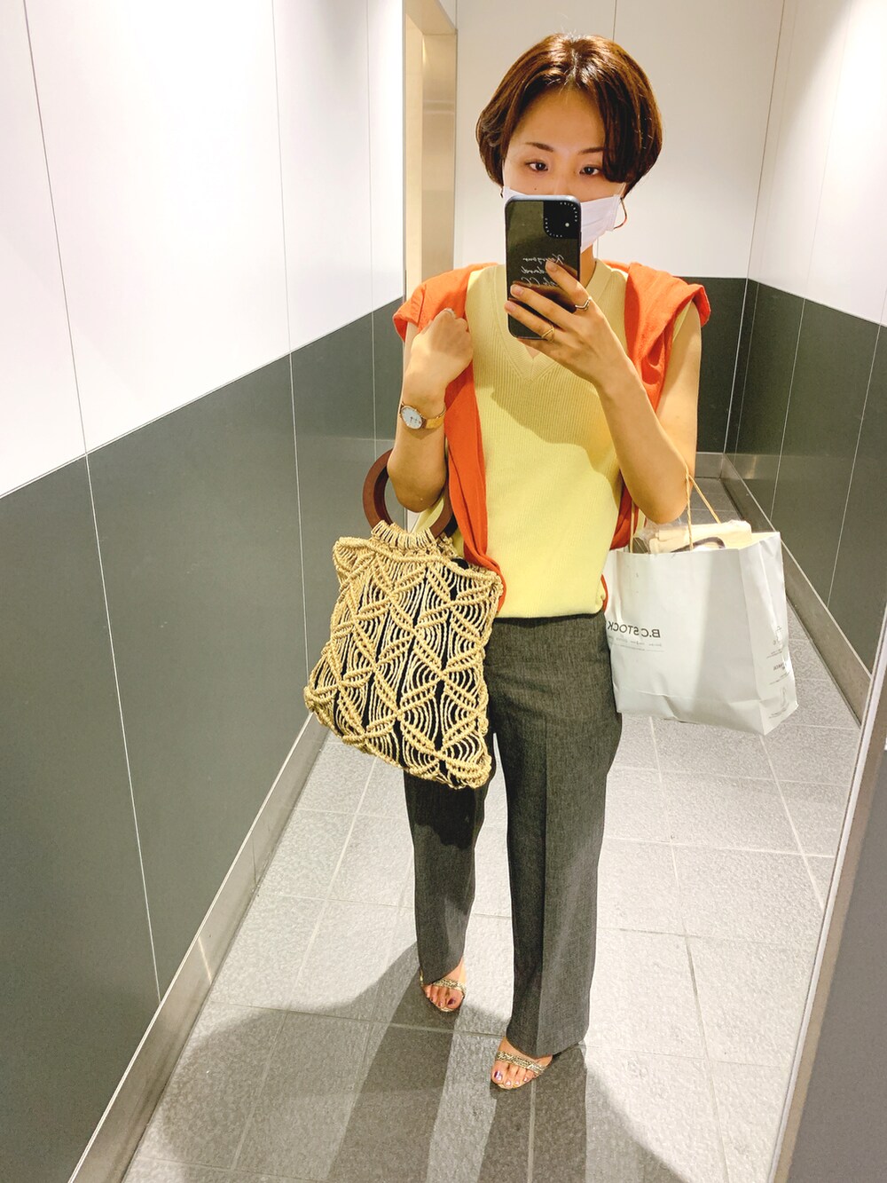 イエロー系のベスト、グレー系のパンツ、オレンジ系のカーディガン/ボレロを着用したレディースの夏コーディネートの2枚目の写真